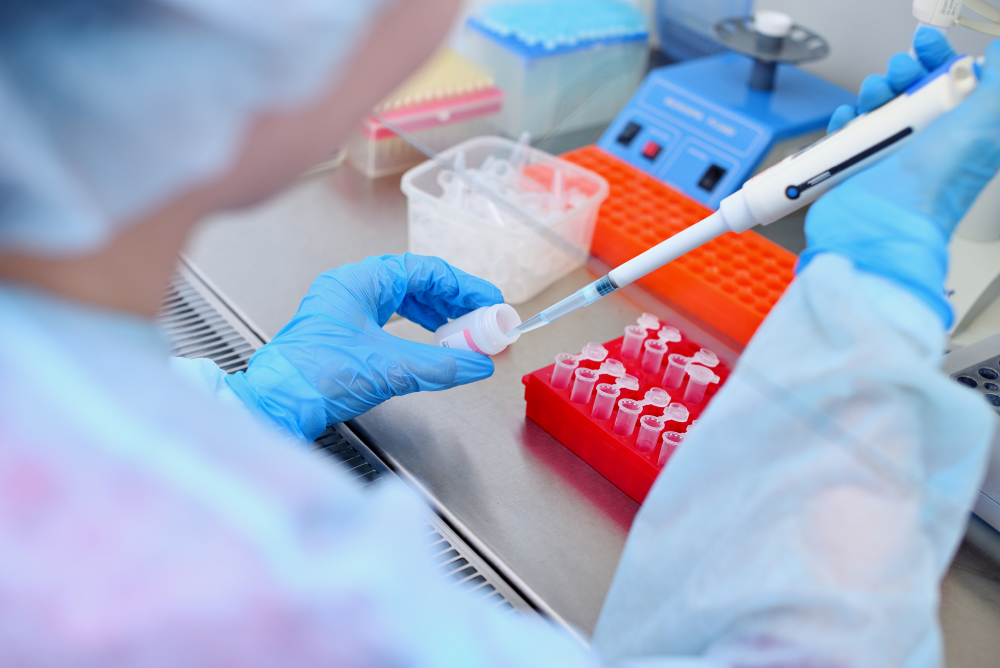 Dna test in the lab. a laboratory technician with a dispenser in his hands is conducting dna analysis in a sterile laboratory behind glass